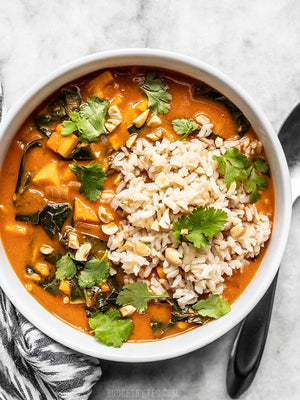 
                  
                    Load image into Gallery viewer, Overhead view of a bowl of west African peanut stew topped with brown rice and cilantro
                  
                