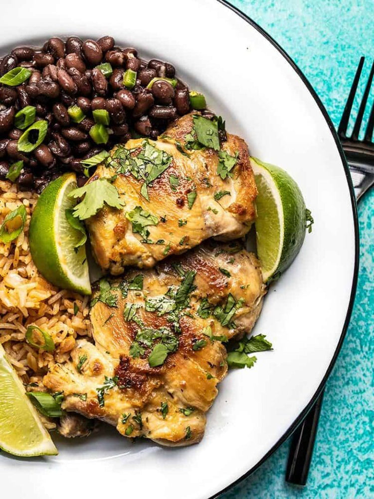 Cilantro lime chicken on a plate with black beans and lime wedges