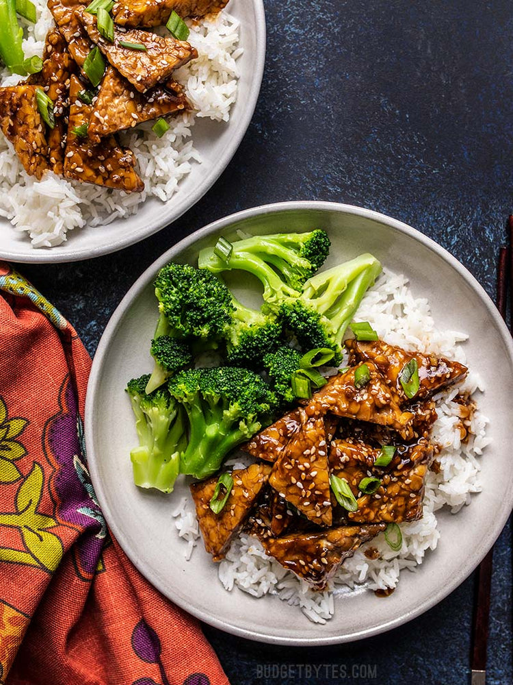 
                  
                    Load image into Gallery viewer, Sesame Tempeh Bowls on two plates with a colorful napkin and black background
                  
                